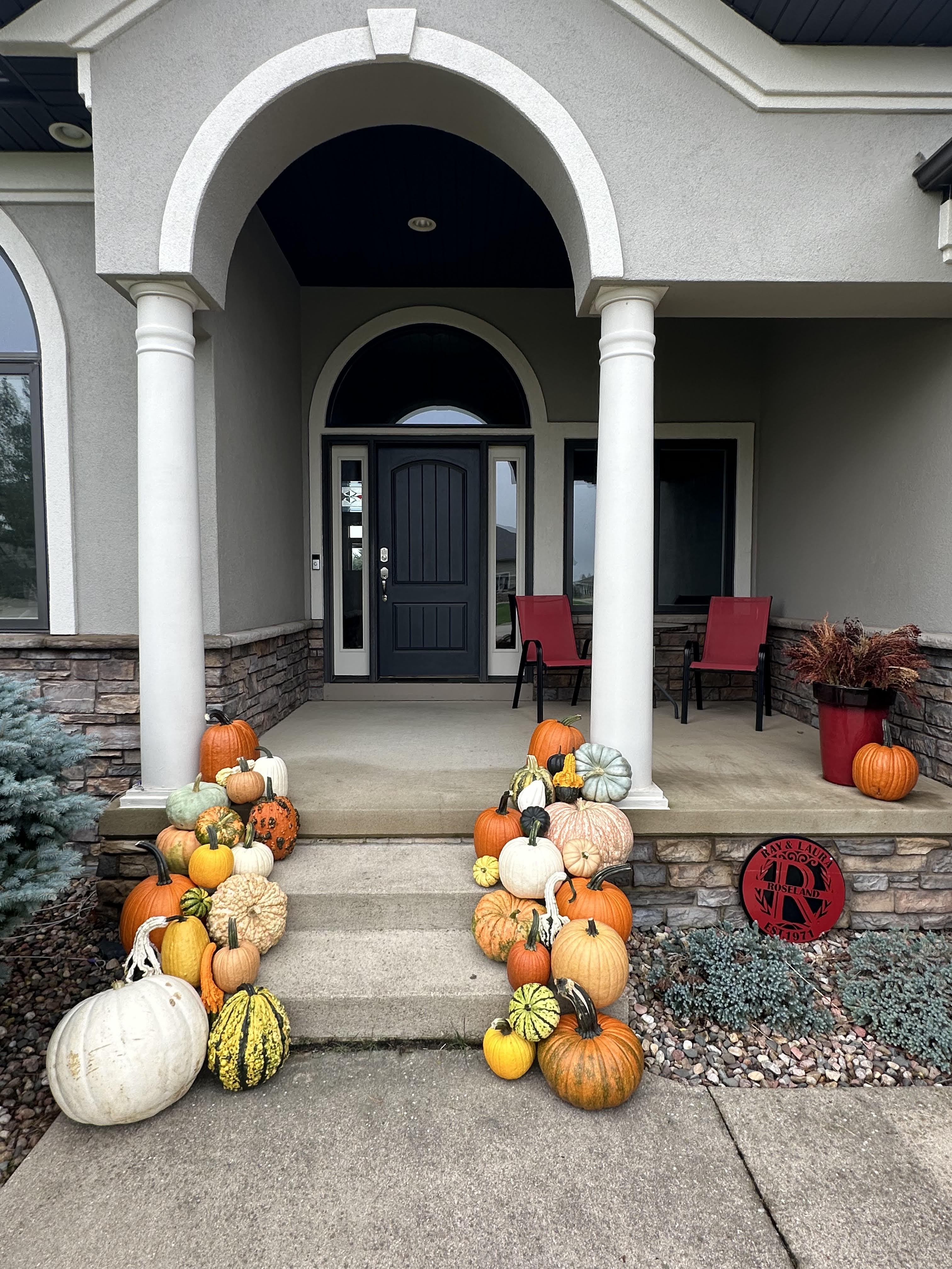Colorful pumpkin and gourd display arranged along a covered front porch